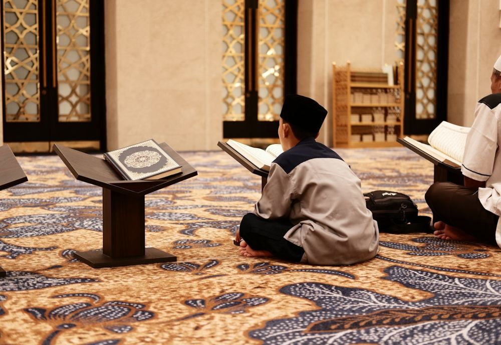 Students reading the Quran on stands in a mosque study hall